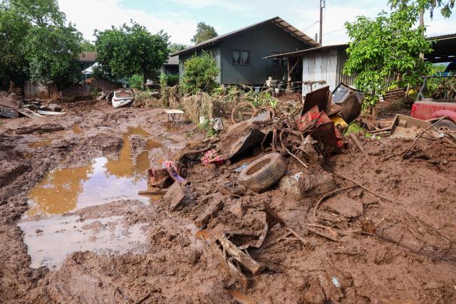Thick mud and debris surround a home after the Kona Low storm flood devastated the Otake Camp community in Waialua, Hawaii on March 22, 2026. Severe rains have battered the region over the weekend prompting officials to order evacuations. (Photo by Marco GARCIA / AFP)