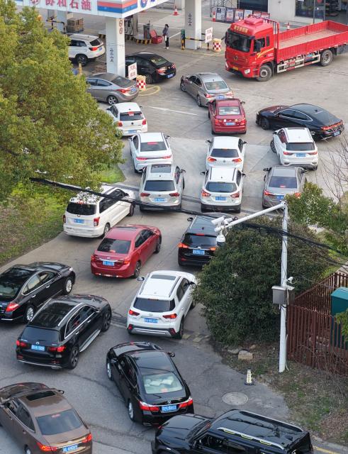 Motorists queue to fill their tanks ahead of a petrol price adjustment expected on March 23, at a petrol station in Suzhou, in China’s eastern Jiangsu province on March 22, 2026. (Photo by CN-STR / AFP) / China OUT