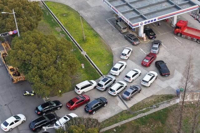 Motorists queue to fill their tanks ahead of a petrol price adjustment expected on March 23, at a petrol station in Suzhou, in China’s eastern Jiangsu province on March 22, 2026. (Photo by CN-STR / AFP) / China OUT