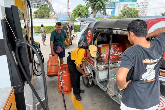 An employee (C) pumps liquefied petroleum gas (LPG) into the vehicle of a customer at a fuel station in Phnom Penh on March 23, 2026. A major energy supplier in Cambodia has said it will halt sales of liquefied petroleum gas from the start of next month due to supply disruptions resulting from the Middle East war. (Photo by TANG CHHIN Sothy / AFP)