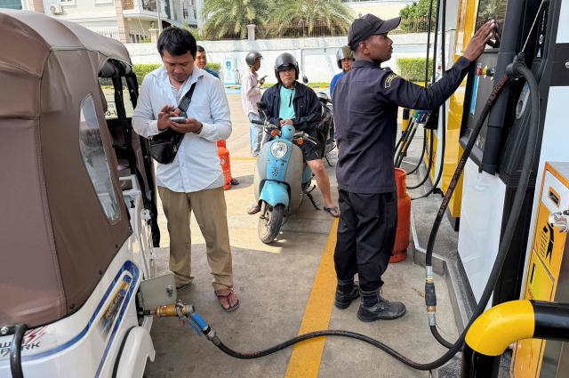 An employee (R) pumps liquefied petroleum gas (LPG) into the vehicle of a customer at a fuel station in Phnom Penh on March 23, 2026. A major energy supplier in Cambodia has said it will halt sales of liquefied petroleum gas from the start of next month due to supply disruptions resulting from the Middle East war. (Photo by TANG CHHIN Sothy / AFP)