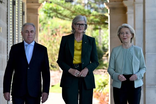 European Commission President Ursula von der Leyen (R) walks with Australia's Governor-General Sam Mostyn (C) and Australia's Trade Minister Don Farrell (L) along the colonnaded verandah at Admiralty House in Sydney on March 23, 2026. (Photo by Saeed KHAN / AFP)