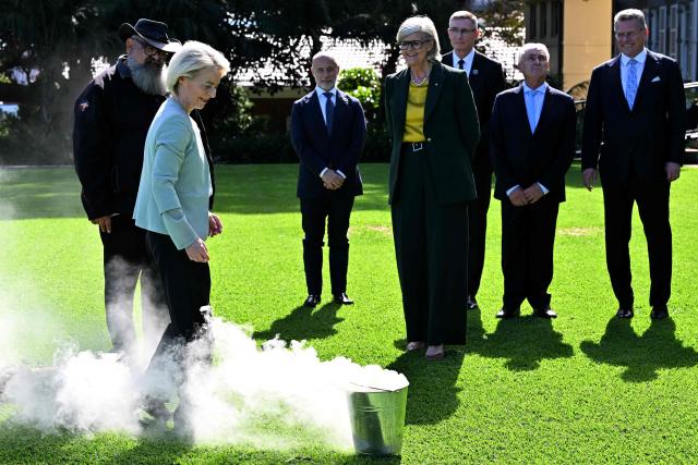 European Commission President Ursula von der Leyen (2nd L) participates in a traditional Aboriginal smoking ceremony along with Australia’s Governor-General Sam Mostyn (C) during a visit at Admiralty House in Sydney on March 23, 2026. (Photo by Saeed KHAN / AFP)
