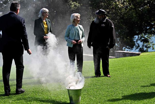 European Commission President Ursula von der Leyen (C) participates in a traditional Aboriginal smoking ceremony along with Australia's Governor-General Sam Mostyn (2nd L) at Admiralty House in Sydney on March 23, 2026. (Photo by Saeed KHAN / AFP)