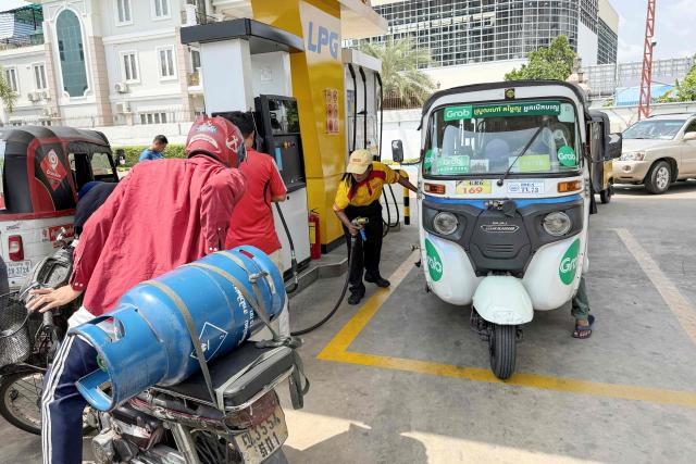 An employee (C) prepares to pump liquefied petroleum gas (LPG) into the vehicle of a customer at a fuel station in Phnom Penh on March 23, 2026. A major energy supplier in Cambodia has said it will halt sales of liquefied petroleum gas from the start of next month due to supply disruptions resulting from the Middle East war. (Photo by TANG CHHIN Sothy / AFP)