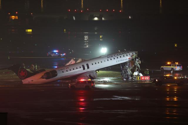 TOPSHOT - Emergency personnel respond to an Air Canada Express CRJ-900 that is sitting on the runway after colliding with a Port Authority fire truck at LaGuardia Airport in New York, on March 23, 2026. Air Canada Express flight AC8646 originated from Montreal and collided with the fire truck during landing. (Photo by ANGELA WEISS / AFP)