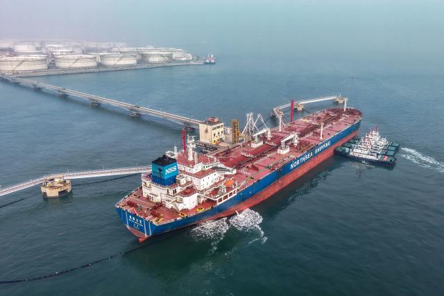 Tugboats move a crude oil tanker to its berth at the oil terminal at the port in Qingdao, in China’s eastern Shandong province on March 23, 2026. (Photo by CN-STR / AFP) / China OUT
