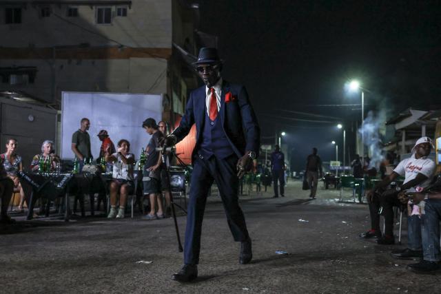 A sapeur walks in a street near their meeting place in Brazzaville on March 22, 2026. Sapology, or Sape (Société des Ambianceurs et des Personnes Élégantes), is a fashion counter-culture that originated in the Congo (Brazzaville and Kinshasa), characterised by the wearing of colourful and eccentric designer suits. A true philosophy, it celebrates elegance, dandyism, an appreciation for colour harmony and the joy of living. (Photo by Daniel BELOUMOU OLOMO / AFP)