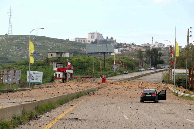A car is parked near a large crater the day after an Israeli airstrike targeted the Qasmiyeh bridge, located on a main highway linking villages in the Tyre district with others further north, after Israel said the bridge was being used by Hezbollah, in southern Lebanon on March 23, 2026. The Lebanese president on March 22, 2026, slammed Israeli strikes on bridges and other infrastructure in the country's south, calling such attacks a "prelude to a ground invasion". Lebanon was drawn into the Middle East war on March 2, when pro-Iran Hezbollah launched rockets towards Israel in response to US-Israeli strikes that killed Iranian supreme leader on February 28, 2026. (Photo by Kawnat HAJU / AFP) / 