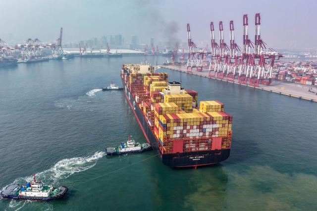 A cargo ship is moved to a berth at the container terminal at the port in Qingdao, in China’s eastern Shandong province on March 23, 2026. (Photo by CN-STR / AFP) / China OUT