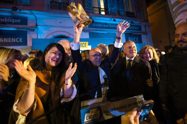 President of UDR parliamentary group and Nice's Union of the Right and the National Rally (RN) mayoral candidate Eric Ciotti (C) holds an eagle with a crown, symbol of the city of Nice, flanked by UDR's MP Christelle D'Intorni (L) and Bernard UDR's MP Bernard Chaix (R) after winning following the results of the second round of France's 2026 municipal elections in Nice, southeastern France on March 22, 2026. (Photo by Valery HACHE / AFP)