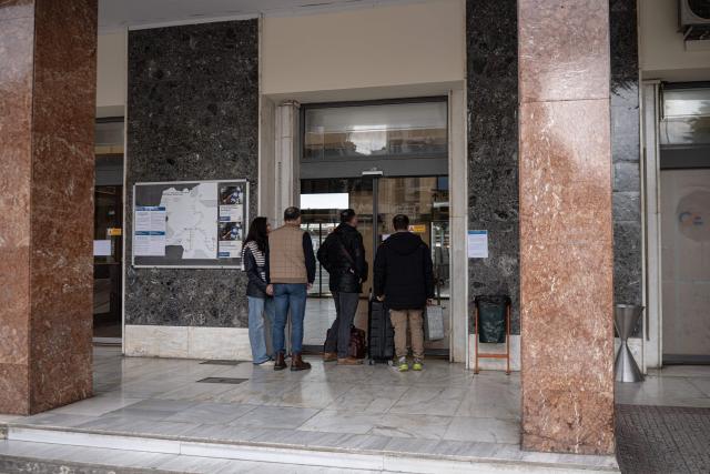 People stand outside the central train station in Athens during a 24-hour general strike on March 23, 2026. A long-awaited trial opened on March 23, 2026 over Greece's worst train tragedy that killed 57 people in 2023, leaving the entire country in shock, an AFP reporter said. Thirty-six people face charges and over 350 witnesses are due to be heard at the trial in the central city of Larissa, near where a freight train and a passenger train collided on February 28, 2023. (Photo by Angelos TZORTZINIS / AFP)