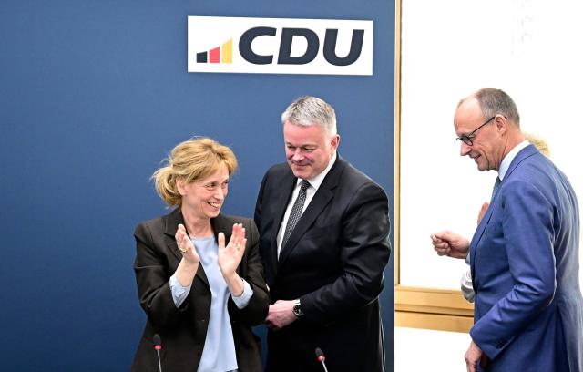 Gordon Schnieder (C), the conservative CDU party's top candidate for state elections in the southwestern state of Rhineland-Palatinate, is applauded by Karin Prien (L), one of the party's vice chairmen, as he arrives with German Chancellor Friedrich Merz (R) to attend a party leadership meeting on March 23, 2026, one day after the vote, at the CDU's headquarters in Berlin. German Chancellor Friedrich Merz's conservatives ousted the centre-left Social Democratic Party in the closely watched state election in which the far right also made big gains, according to exit polls. (Photo by Tobias SCHWARZ / AFP)