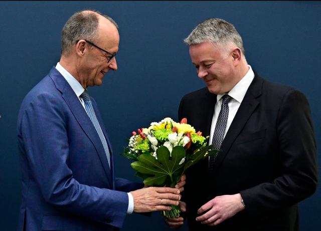 German Chancellor Friedrich Merz gives a bouquet of flowers to Gordon Schnieder, the conservative CDU party's top candidate for state elections in the southwestern state of Rhineland-Palatinate, on March 23, 2026, one day after the vote, at the CDU's headquarters in Berlin. German Chancellor Friedrich Merz's conservatives ousted the centre-left Social Democratic Party in the closely watched state election in which the far right also made big gains, according to exit polls. (Photo by Tobias SCHWARZ / AFP)