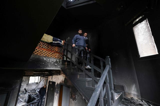 Two Palestinian men walk down the staircase of a burnt out home following a reported attack by Israeli settlers in the village of Deir al-Hatab, east of the city of Nablus, in the Israeli-occupied West Bank on March 23, 2026. Palestinian residents said on March 22, 2026, that Israeli settlers torched buildings and cars in attacks on several villages in the occupied West Bank, with Israel's army condemning "violence of any kind" after the fact.  Violence in the Palestinian West Bank, which Israel has occupied since 1967, has soared since the Hamas attack on Israel triggered the Gaza war in October 2023. (Photo by JAAFAR ASHTIYEH / AFP)