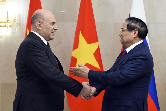 In this pool photograph distributed by the Russian state agency Sputnik, Russia's Prime Minister Mikhail Mishustin (left) greets Vietnamese Prime Minister Pham Minh Chinh ahead of a meeting in Moscow on March 23, 2026. (Photo by Alexander Miridonov / POOL / AFP)