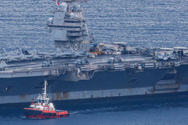 A tugboat escorts the world's largest aircraft carrier USS Gerald R. Ford as it arrives at Souda Bay naval base after having been part of Middle East war operations, on the island of Crete on March 23, 2026. The United States and Israel launched a massive air campaign against Iran in late February following a major US military buildup in the Middle East that included the Ford and another aircraft carrier, the Abraham Lincoln. (Photo by Costas METAXAKIS / AFP)