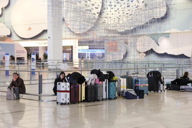 Travelers wait inside Terminal B at LaGuardia Airport during a ground stop following an overnight accident involving an Air Canada Express CRJ-900 that collided with a Port Authority fire truck on the runway, in New York, on March 23, 2026. A plane carrying dozens of people collided with a fire truck on a runway at New York's LaGuardia airport, killing the pilot and co-pilot and causing "serious injuries" to others, authorities said Monday. Due to the crash late Sunday, US aviation authorities halted all flights at LaGuardia, and the port authority said the airport would stay shut until at least 2:00 pm (1800 GMT) "to allow for a thorough investigation." (Photo by TIMOTHY A.CLARY / AFP)