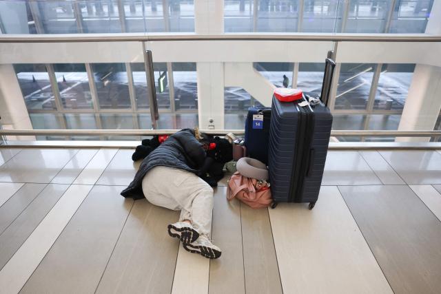 Travelers wait inside Terminal B at LaGuardia Airport during a ground stop following an overnight accident involving an Air Canada Express CRJ-900 that collided with a Port Authority fire truck on the runway, in New York, on March 23, 2026. A plane carrying dozens of people collided with a fire truck on a runway at New York's LaGuardia airport, killing the pilot and co-pilot and causing "serious injuries" to others, authorities said Monday. Due to the crash late Sunday, US aviation authorities halted all flights at LaGuardia, and the port authority said the airport would stay shut until at least 2:00 pm (1800 GMT) "to allow for a thorough investigation." (Photo by TIMOTHY A.CLARY / AFP)