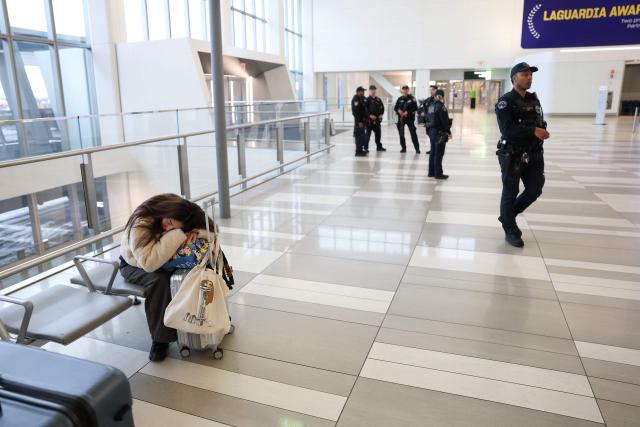 Travelers wait inside Terminal B at LaGuardia Airport during a ground stop following an overnight accident involving an Air Canada Express CRJ-900 that collided with a Port Authority fire truck on the runway, in New York, on March 23, 2026. A plane carrying dozens of people collided with a fire truck on a runway at New York's LaGuardia airport, killing the pilot and co-pilot and causing "serious injuries" to others, authorities said Monday. Due to the crash late Sunday, US aviation authorities halted all flights at LaGuardia, and the port authority said the airport would stay shut until at least 2:00 pm (1800 GMT) "to allow for a thorough investigation." (Photo by TIMOTHY A.CLARY / AFP)