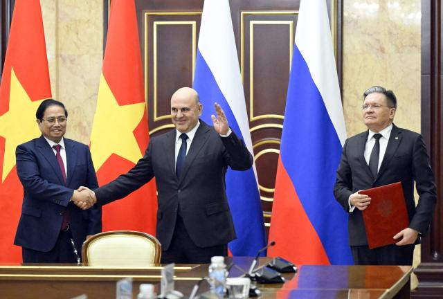 In this pool photograph distributed by the Russian state agency Sputnik, Russian Prime Minister Mikhail Mishustin (centre), Vietnamese Prime Minister Pham Minh Chinh (left) and Director General of Russia's State Atomic Energy Corporation Rosatom Alexei Likhachev (right) take part in a signing ceremony of a cooperation agreement for the construction of a nuclear power plant on the territory of Vietnam, in Moscow on March 23, 2026. (Photo by Alexander Miridonov / POOL / AFP)