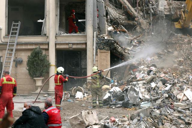 Iranian firefighters douce the rubble of a destroyed residential building as a search is carried out,  in northern Tehran on March 23, 2026. A series of strong explosions were heard in the Iranian capital on March 23, an AFP journalist said, as the war with the United States and Israel raged for its fourth week. On February 28, Israel and the United States launched strikes on Iran killing its supreme leader and triggering a war that spread across the Middle East and unleashed chaos across global markets and sent oil prices soaring. (Photo by AFP) / 
