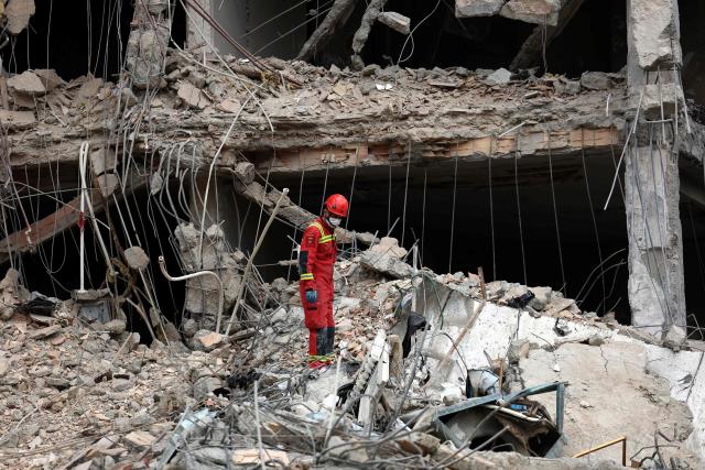 An Iranian firefighter walks on the rubble of a destroyed residential building as a search is carried out,  in northern Tehran on March 23, 2026. A series of strong explosions were heard in the Iranian capital on March 23, an AFP journalist said, as the war with the United States and Israel raged for its fourth week. On February 28, Israel and the United States launched strikes on Iran killing its supreme leader and triggering a war that spread across the Middle East and unleashed chaos across global markets and sent oil prices soaring. (Photo by AFP) / 
