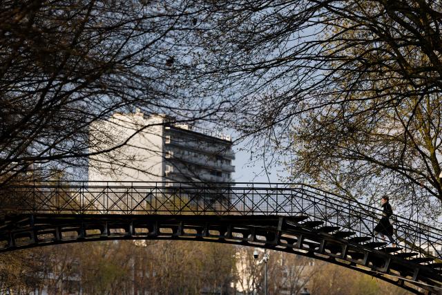 A pedestrian crosses a footbridge over the canal de l'Ourcq canal in Paris on March 22, 2026. (Photo by JOEL SAGET / AFP)