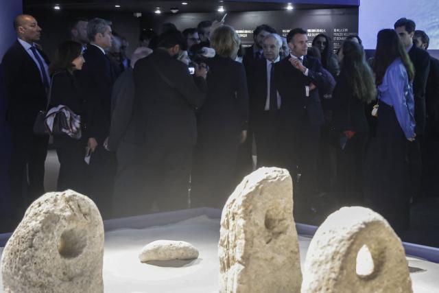 France's President Emmanuel Macron (top C) visits the exhibition "Byblos, Lebanon's Millennial City," at the Arab World Institute (IMA) in Paris, on March 23, 2026. France's President inaugurated on March 23, 2026, an exhibition dedicated to Byblos, the ancient city north of Beirut, organized by the Arab World Institute (IMA), at a time when Lebanon is plunged into a new war that has disrupted the arrival of the works being shown in Paris. The exhibition features some 400 pieces. (Photo by Christophe PETIT TESSON / POOL / AFP)