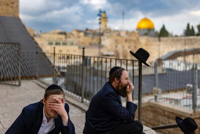 Two Jewish men pray overlooking the Western Wall and the Dome of the Rock in Jerusalem's Old City on March 23, 2026. Since the United States and Israel unleashed strikes on Iran on February 28, war has spread across the Middle East, with casualties reported in countries across the region. (Photo by Odd ANDERSEN / AFP) / 