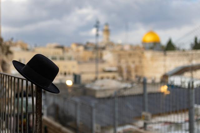 The hat of a Jewish man praying is seen placed on a balustrade overlooking the Western Wall and the Dome of the Rock in Jerusalem's Old City, on March 23, 2026. Since the United States and Israel unleashed strikes on Iran on February 28, war has spread across the Middle East, with casualties reported in countries across the region. (Photo by Odd ANDERSEN / AFP) / 