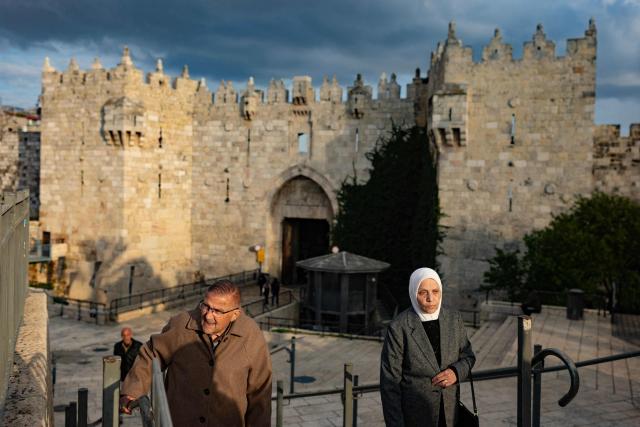 An elderly couple walks up steps outside Damascus Gate in Jerusalem's Old City on March 23, 2026. Since the United States and Israel unleashed strikes on Iran on February 28, war has spread across the Middle East, with casualties reported in countries across the region. (Photo by Odd ANDERSEN / AFP) / 