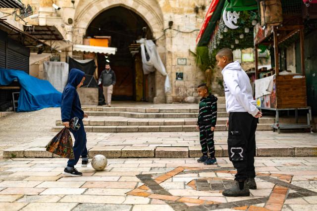 Palestinian boys play football near Damascus Gate in Jerusalem's Old City on March 23, 2026. Since the United States and Israel unleashed strikes on Iran on February 28, war has spread across the Middle East, with casualties reported in countries across the region. (Photo by Odd ANDERSEN / AFP) / 
