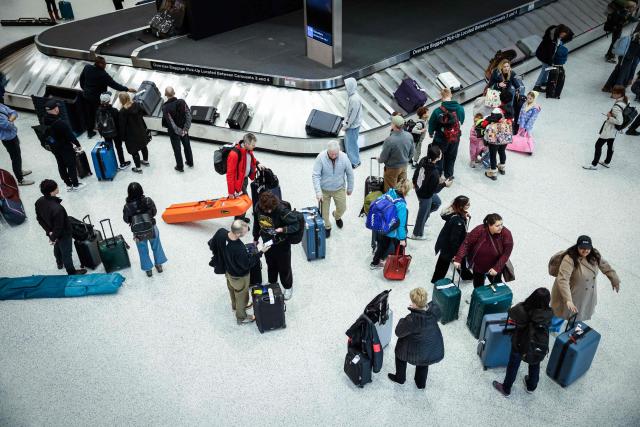 Travelers gather at a baggage claim station at Newark International Airport in Newark, New Jersey, on March 23, 2026. Immigration agents will be deployed in US airports beginning Monday, aiming to alleviate soaring congestion at security screenings amid a weeks-long budget standoff over President Donald Trump's mass deportation drive, officials said. (Photo by kena betancur / AFP)