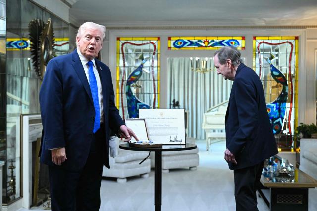 US President Donald Trump gestures to the Medal of Freedom that he awarded postumously to Elvis Presely in 2010 as he visits Graceland, the estate of Elvis Presley, in Memphis, Tennessee on March 23, 2026. (Photo by SAUL LOEB / AFP)