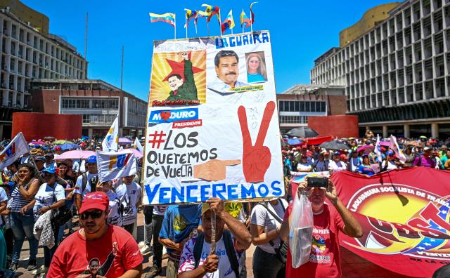 An activist holds a sign reading "We want them back. We will defeat" during a march demanding the complete lifting of US sanctions, in Caracas, on March 23, 2026. (Photo by Juan BARRETO / AFP)