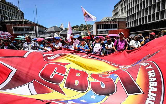 People take part in a march demanding the complete lifting of US sanctions, in Caracas, on March 23, 2026. (Photo by Juan BARRETO / AFP)