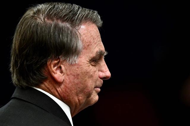 (FILES) Former Brazilian President Jair Bolsonaro gestures during a session of the Brazilian Supreme Court judging the participation of those accused of the attempted coup d'йtat in January 2023, in Brasilia on June 9, 2025. Former Brazilian President Jair Bolsonaro, who was hospitalized with bronchopneumonia, was released from intensive care on March 23, 2026, one of his doctors reported, as he awaits the Supreme Court’s decision on whether to grant him house arrest. (Photo by EVARISTO SA / AFP)