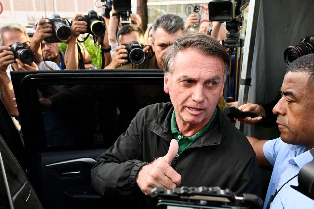 (FILES) Former Brazilian President Jair Bolsonaro gives the thumbs up as he leaves the Federal Police headquarters after being questioned as part of an investigation into one of his sons, who is suspected of having asked the US government to sanction senior Brazilian officials by denouncing his father's alleged persecution, in Brasilia, on June 5, 2025. Former Brazilian President Jair Bolsonaro, who was hospitalized with bronchopneumonia, was released from intensive care on March 23, 2026, one of his doctors reported, as he awaits the Supreme Courts decision on whether to grant him house arrest. (Photo by EVARISTO SA / AFP)