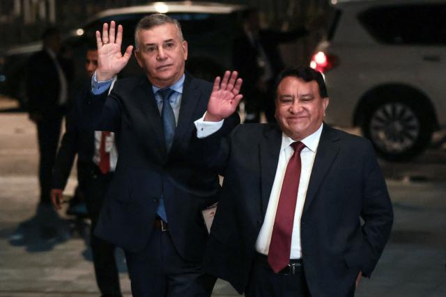 Peru's presidential candidate Jose Luna Galvez (R), from the Podemos Peru party, waves as he arrives at the Lima Convention Center ahead of the first round of debates on tackling crime and corruption in Lima on March 23, 2026, ahead of the April 12 general election. (Photo by Connie FRANCE / AFP)