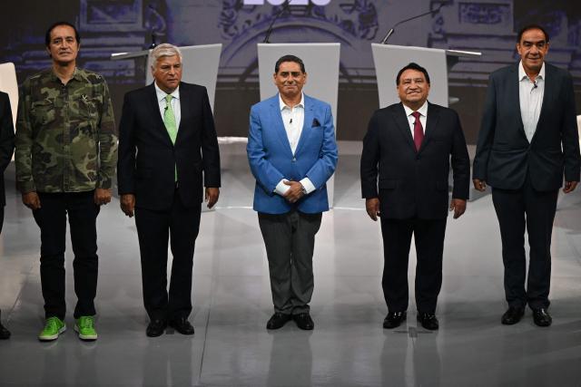 (L to R) Peru's presidential candidates: Alex Gonzales, for the Democrata Verde party; Fernando Olivera, for the Frente de la Esperanza party; Carlos Alvarez, for the Pais Para Todos party; Jose Luna Galvez, for the Podemos Peru party; and Yonhy Lescano, for the Cooperacion Popular party, stand during the first round of debates on tackling crime and corruption at the Lima Convention Center in Lima on March 23, 2026, ahead of the April 12 general election. (Photo by ERNESTO BENAVIDES / AFP)