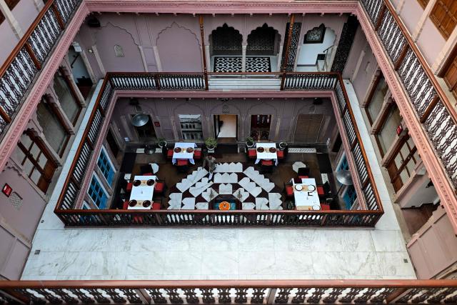 This photograph taken on February 2, 2026 shows a hospitality staff walking across a courtyard of the Dharampura Haveli, an 18th-century haveli-turned-heritage hotel in the old quarters of Delhi. Once the grand residences of Mughal-era nobility, the Indian capital's haveli homes now stand at fragile crossroads -- a handful lovingly restored but many more sliding quietly into ruin. (Photo by Manan VATSYAYANA / AFP)
