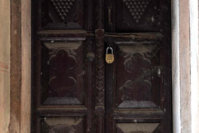 This photograph taken on February 5, 2026 shows a lock on a wooden door of a century-old haveli in the old quarters of Delhi. Once the grand residences of Mughal-era nobility, the Indian capital's haveli homes now stand at fragile crossroads -- a handful lovingly restored but many more sliding quietly into ruin. (Photo by Manan VATSYAYANA / AFP)