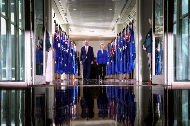 European Commission President Ursula von der Leyen (R) and Australian Prime Minister Anthony Albanese pass a row of flags as the walk out of the House of Representatives in Parliament House in Canberra on March 24, 2026. (Photo by DAVID GRAY / AFP)