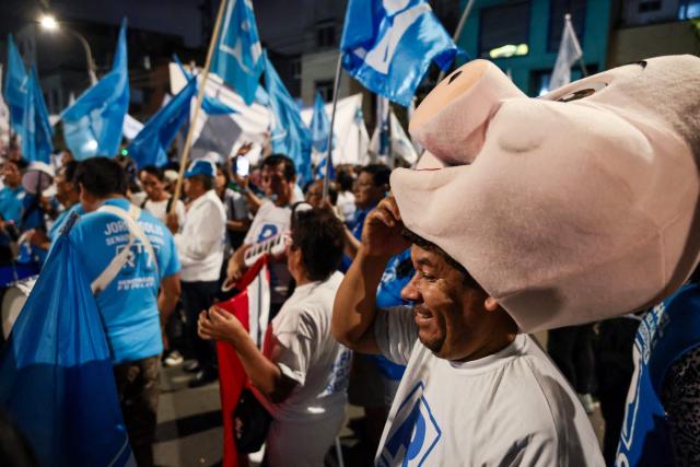 A supporter of Peru's presidential candidate Rafael Lopez Aliaga, for the Renovacion Popular party, wears a pig mask outside the Lima Convention Center during the first round of debates on tackling crime and corruption in Lima on March 23, 2026, ahead of the April 12 general election. (Photo by Connie FRANCE / AFP)