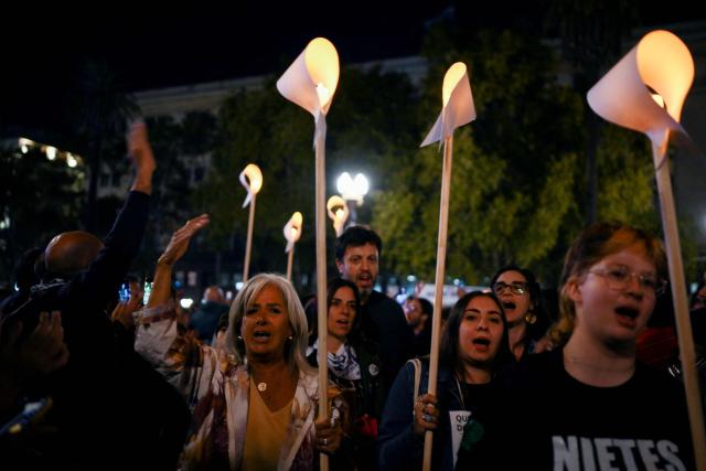 People hold illuminated white scarves as they gather in the Plaza de Mayo square in Buenos Aires on March 23, 2026, to attend a vigil one day before the 50th anniversary of the military coup that ushered in the military dictatorship (1976–1983). (Photo by Luis ROBAYO / AFP)