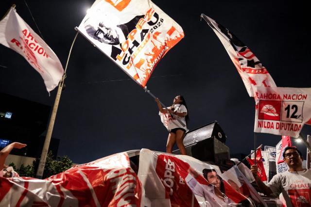 A supporter of Peru's presidential candidate Alfonso Lopez-Chau, from the Ahora Nacion party, waves a flag outside the Lima Convention Center during the first round of debates on tackling crime and corruption in Lima on March 23, 2026, ahead of the April 12 general election. (Photo by Connie FRANCE / AFP)