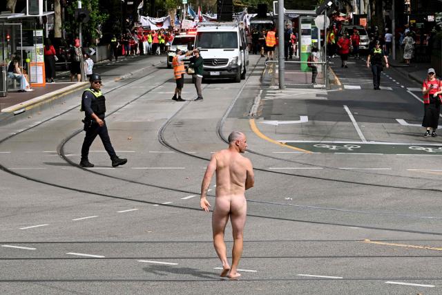 EDITORS NOTE: Graphic content / A man walks naked as teachers march through Melbourne's city centre to protest over pay and conditions on March 24, 2026. Tens of thousands of public school teachers went on strike for the first time in thirteen years following a pay dispute with the state government, closing or disrupting some 500 state schools. (Photo by William WEST / AFP)