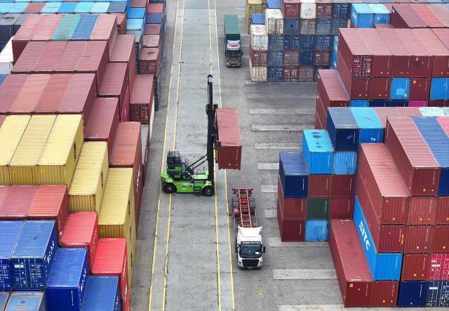 An operator uses a heavy equipment to move containers at the container terminal in Lianyungang, eastern China's Jiangsu province on March 24, 2026. (Photo by CN-STR / AFP) / China OUT