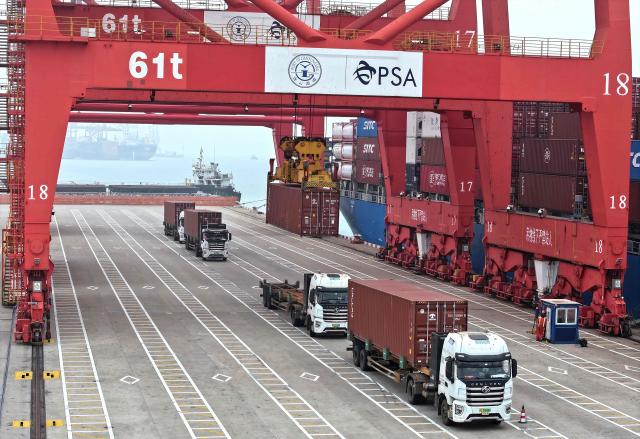 Trucks move containers at the container terminal in Lianyungang, eastern China's Jiangsu province on March 24, 2026. (Photo by CN-STR / AFP) / China OUT